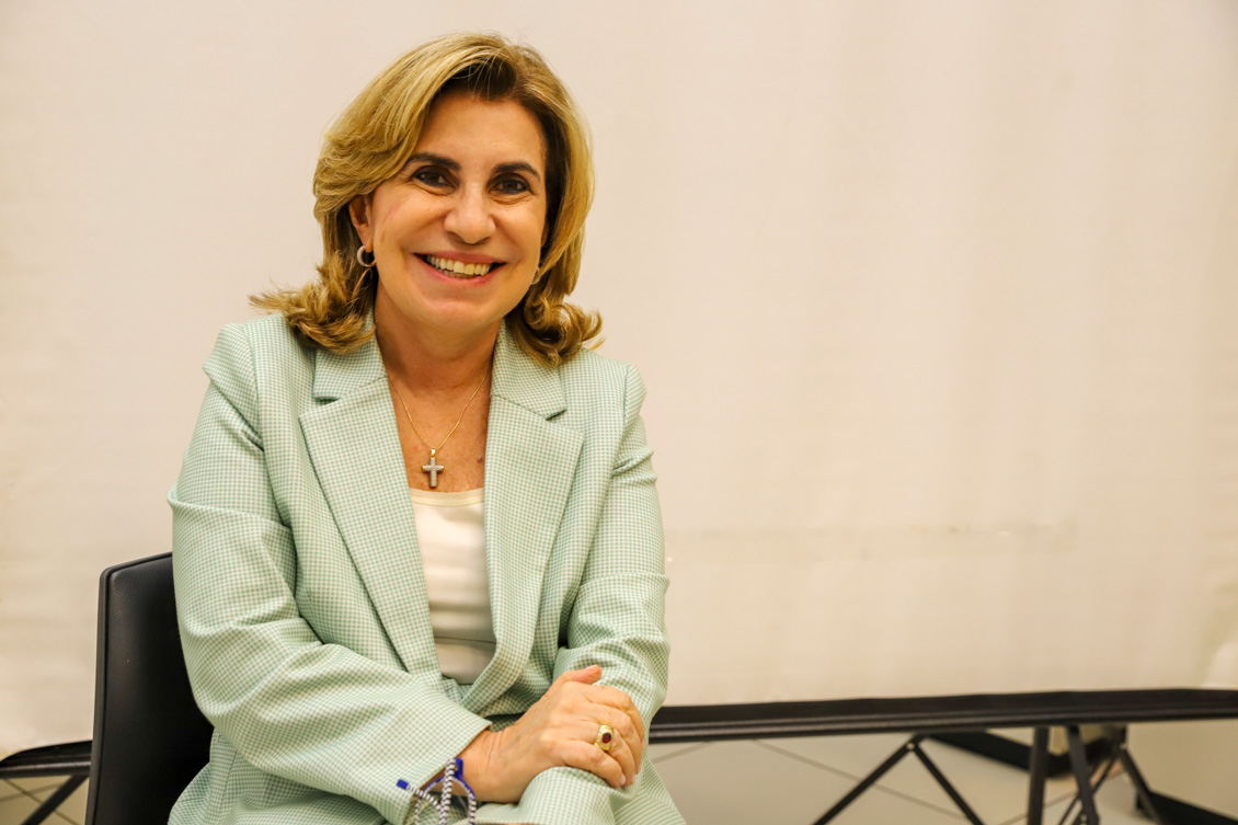 "Dra. Ana Paula está sentada em uma cadeira, sorridente"