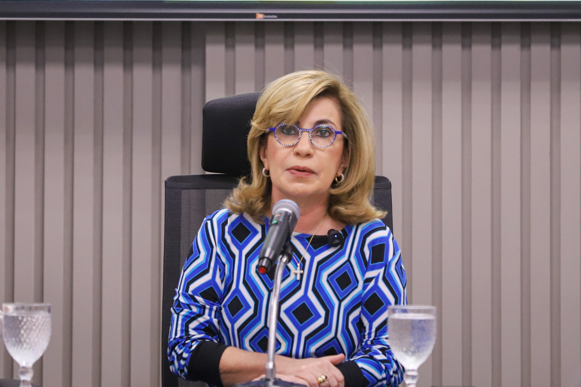 "Dra, Ana Paula está na mesa alta, falando ao microfone"
