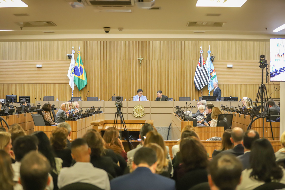 "Público em primeiro plano e ao fundo, o ministro Vieira de Mello ao lado de Márcio Pochmann na mesa alta"