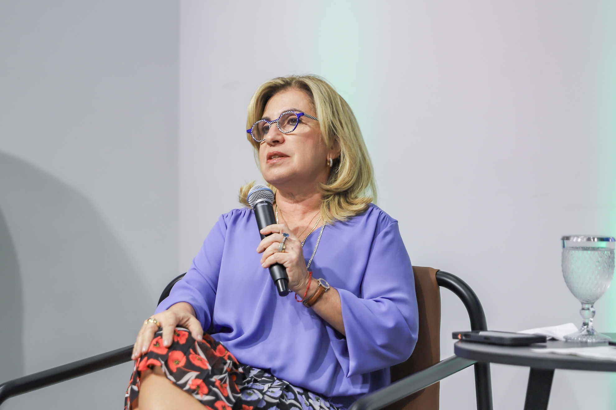 "A presidente Ana Paula fala ao microfone, em pé"