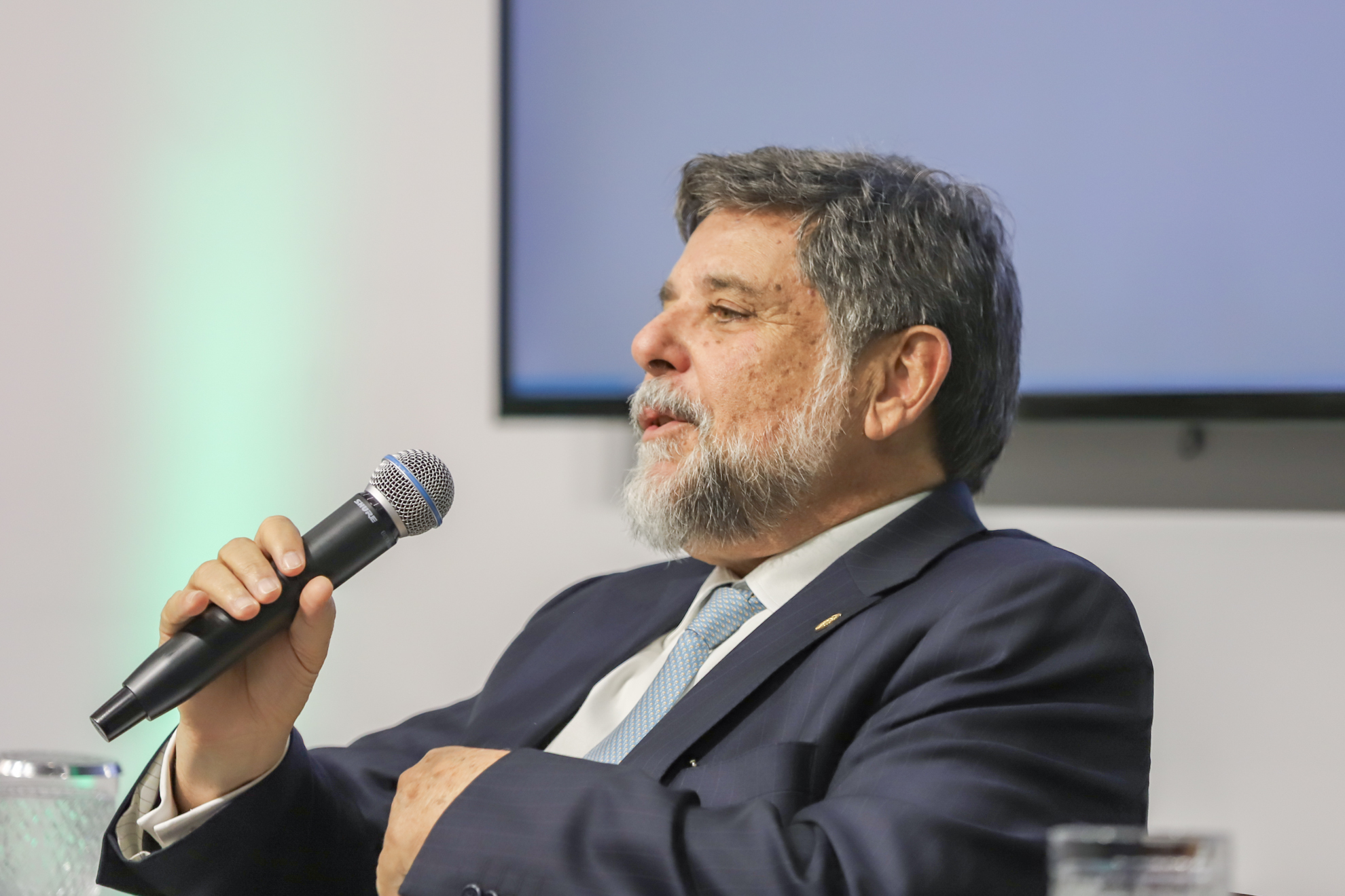 "O ministro fala ao microfone, em pé"