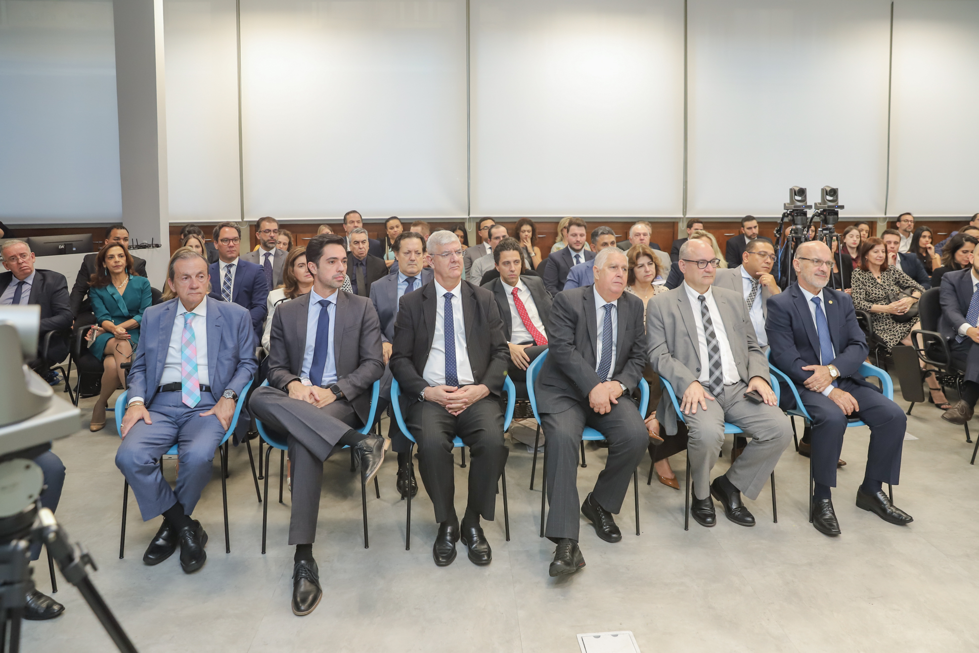 "Mulheres e homens sentados, no auditório"