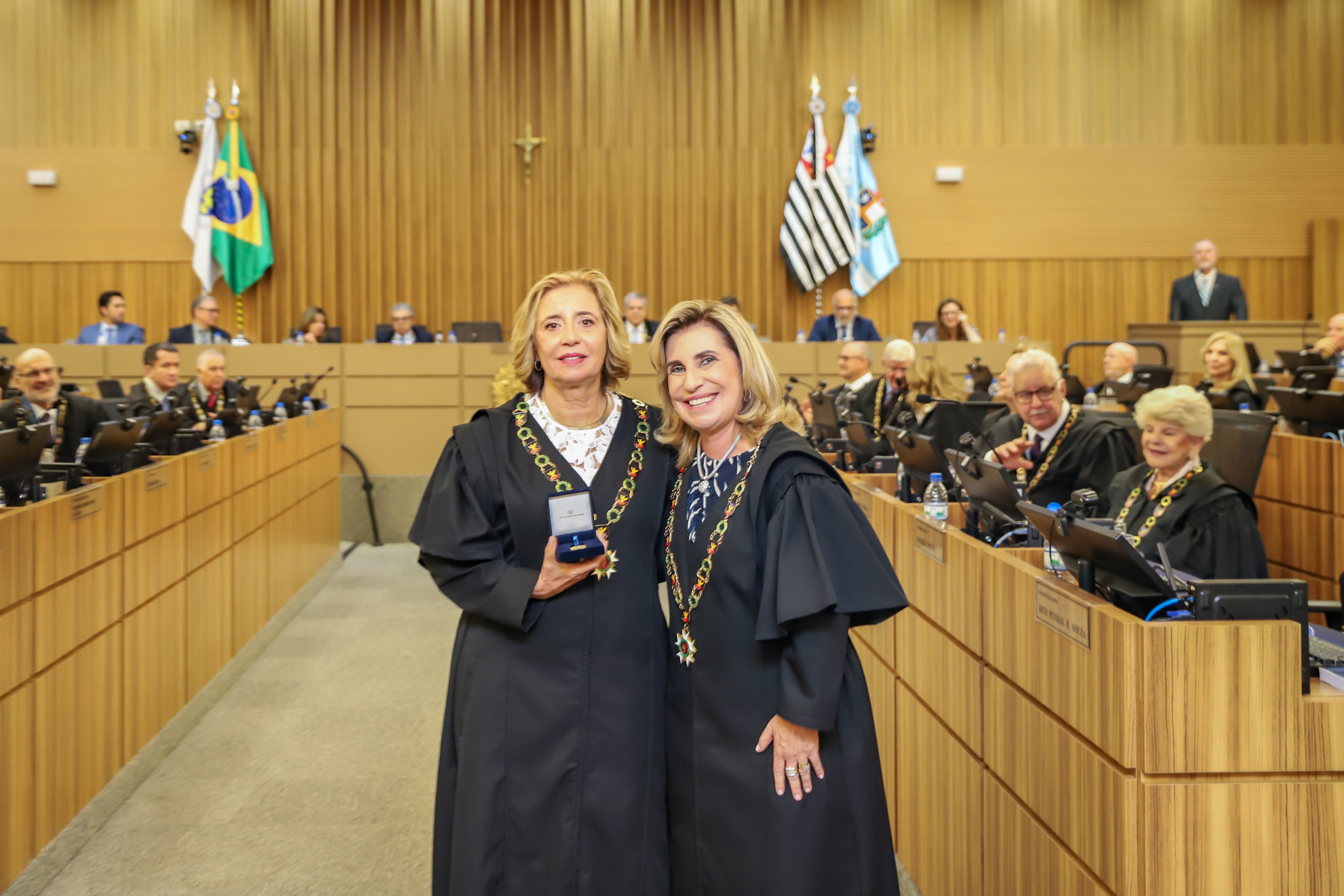 "Duas magistradas posam para a foto. Uma segura a medalha."
