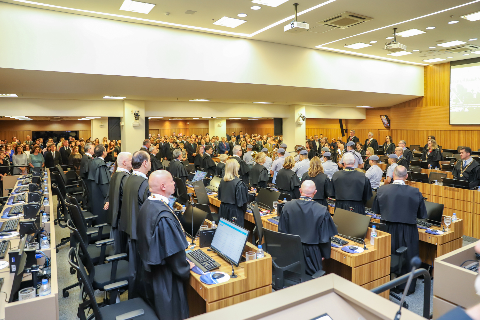 "Foto geral do Plenário, todos em pé, com a banda da PM no centro."