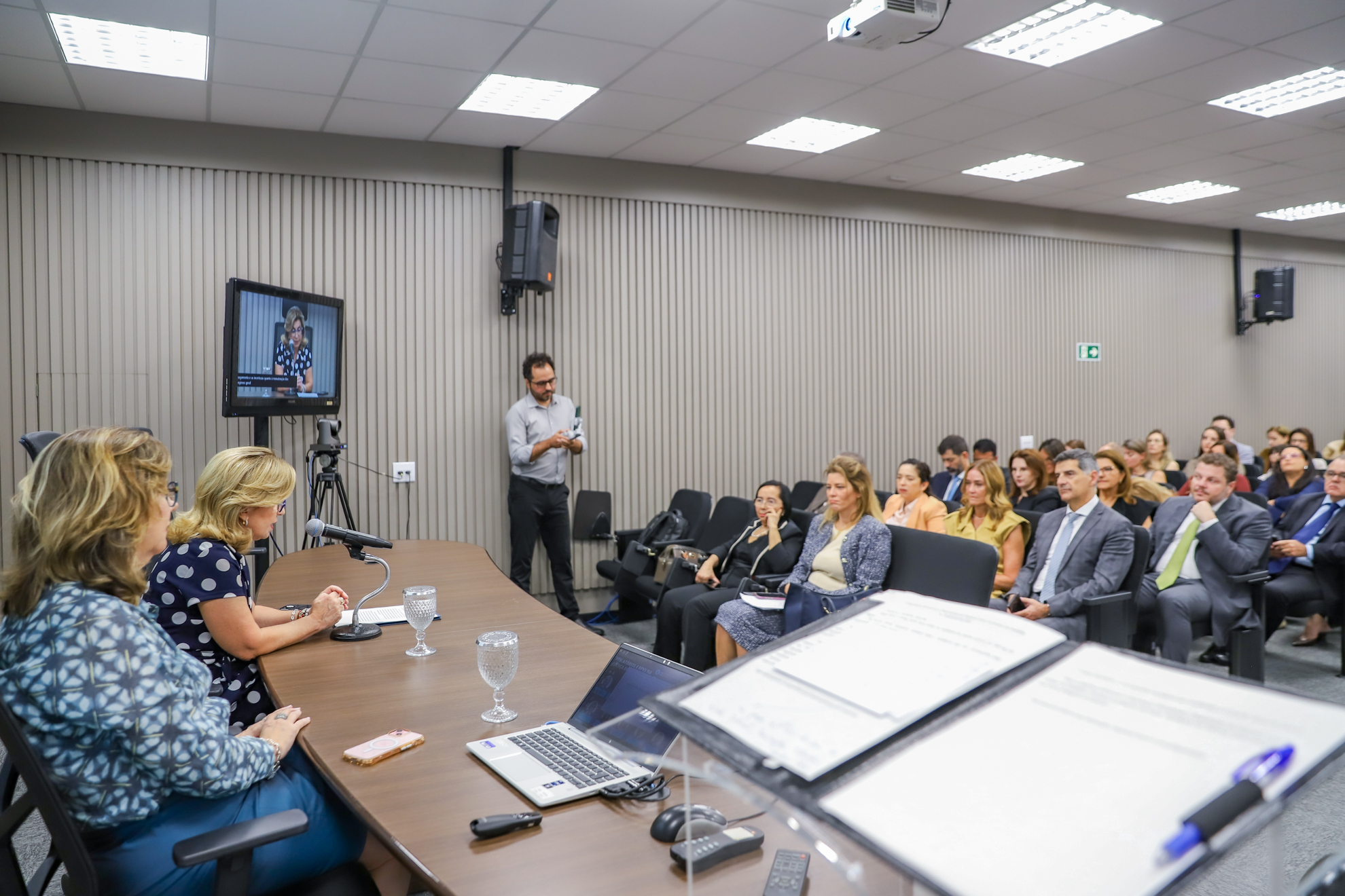 "Foto da mesa alta com Dra. Ana Paula e Dra. Eleonora, mostrando também parte da plateia"