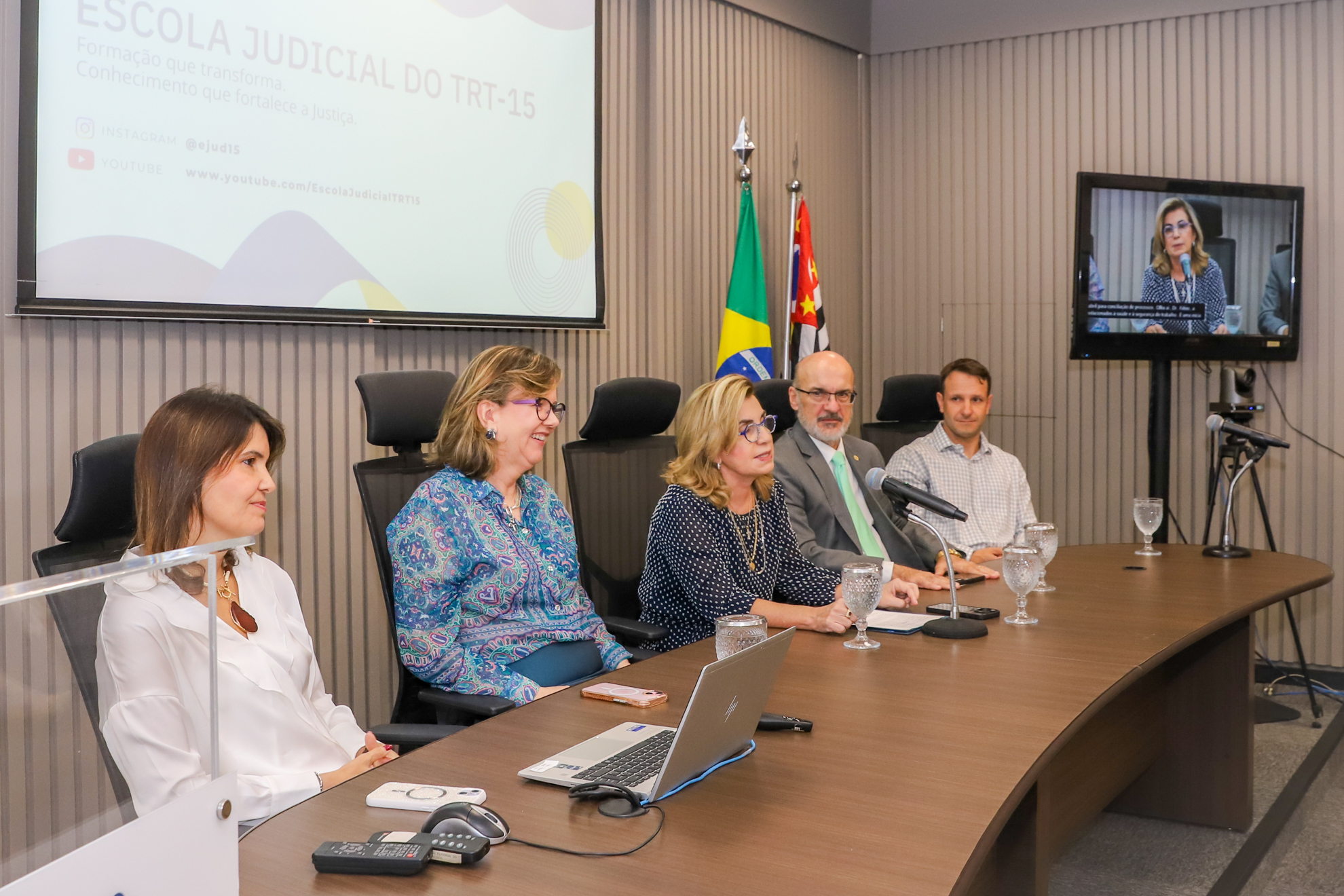 "#ParaTodosVerem: cinco pessoas sentadas atrás da mesa alta do auditório da Ejud15"