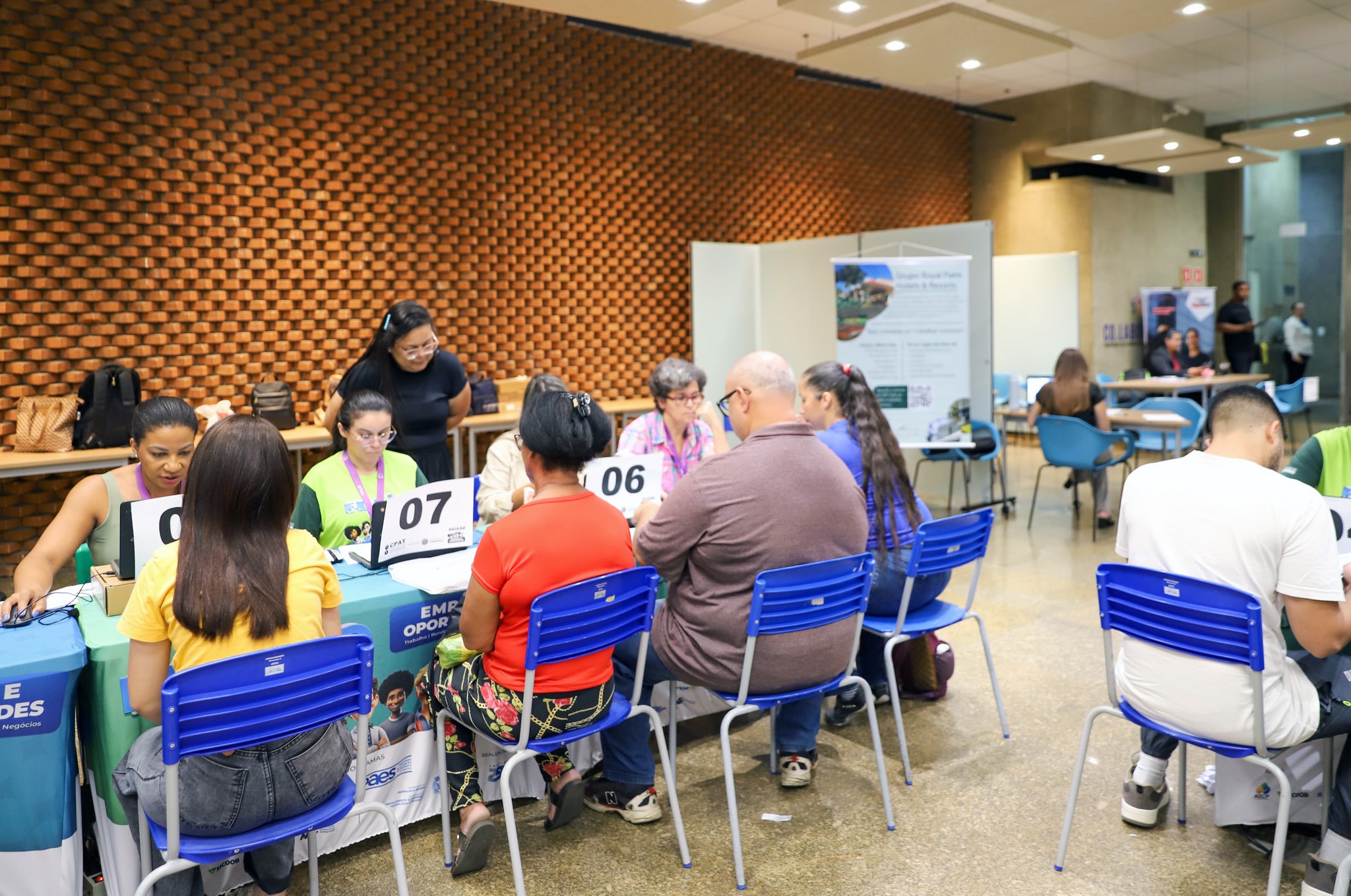 "Foto geral do evento, com pessoas à mesa passando por triagem"