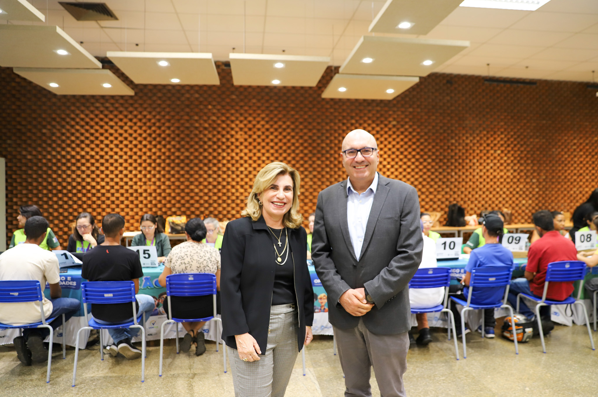 "Dra. Ana Paula e prefeito Dário posam para foto em frente a uma mesa lotada de trabalhadores sendo atendidos"