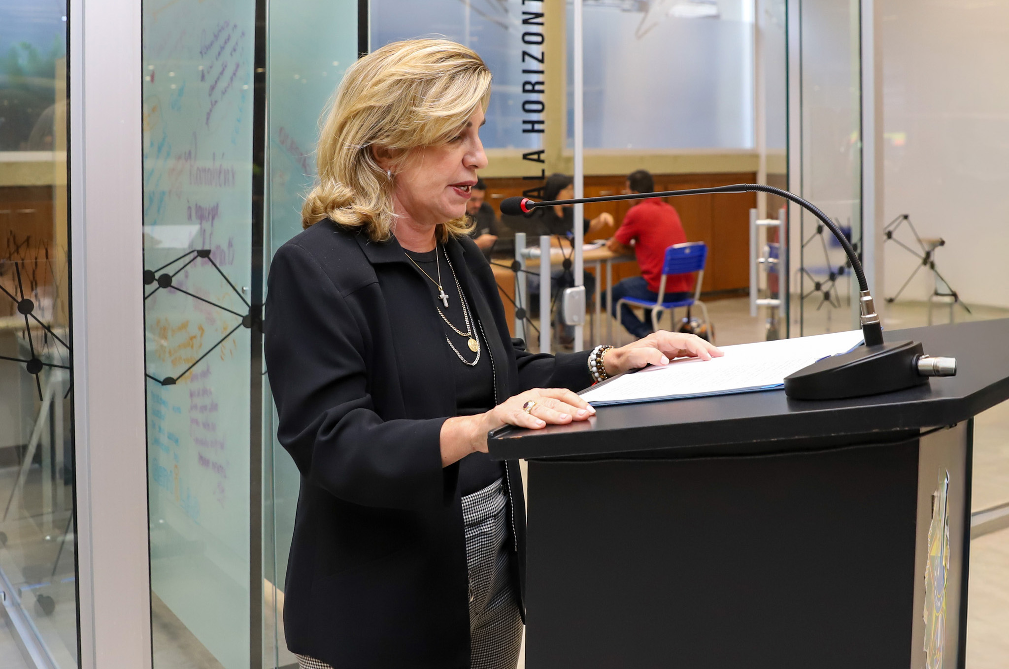 "Dra. Ana Paula fala ao microfone no púlpito"