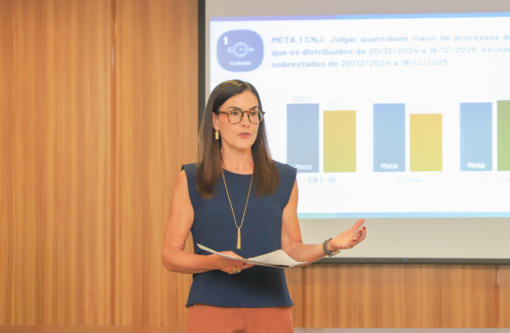 "desembargadora Andrea Guelfi segura uma folha de papel e fala para o público"