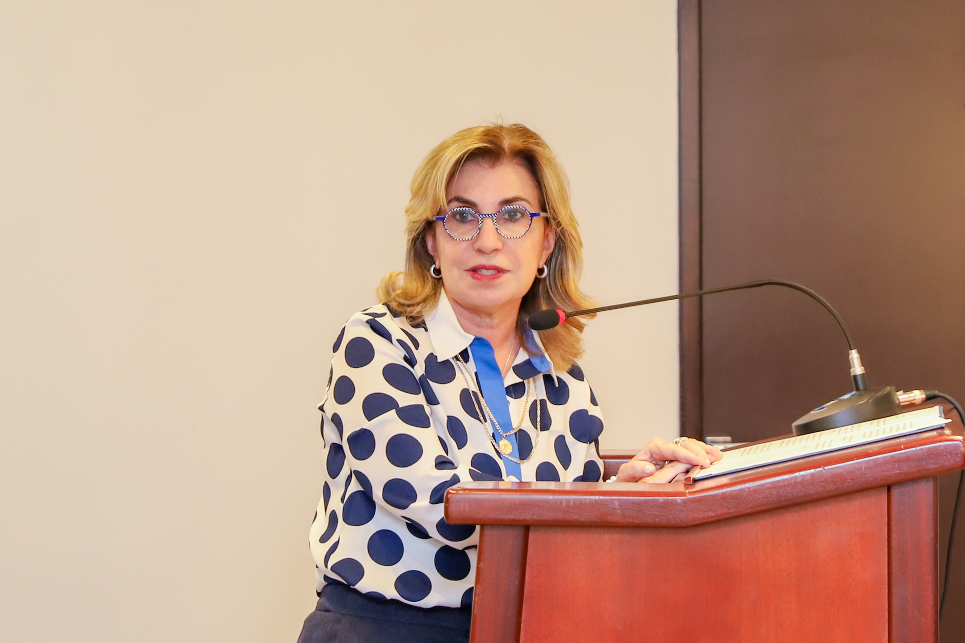 "Dra. Ana Paula fala ao microfone no púlpito"