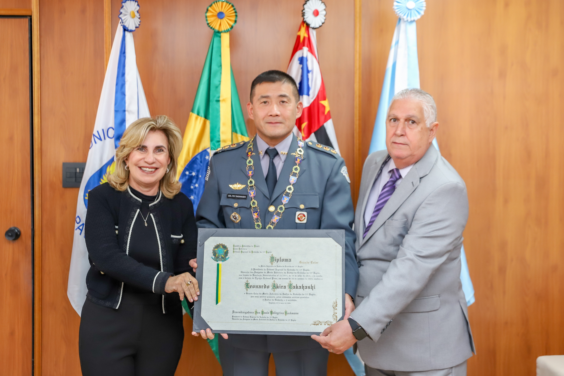 "Coronel Takahashi, com o Grande Colar e segurando o certificado, posa para foto ao lado da Dra. Ana e Dr. Helcio