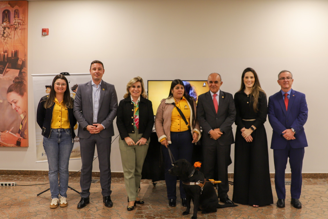 "foto posada das autoridades e representantes da Adimax com cão-guia preto"