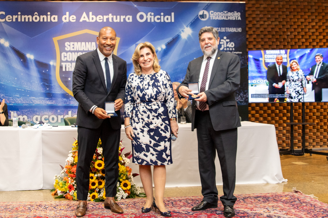 "Mauro Silva e ministro Caputo seguram a medalha comemorativa presenteada pela Dra. Ana Paula que está entre eles"