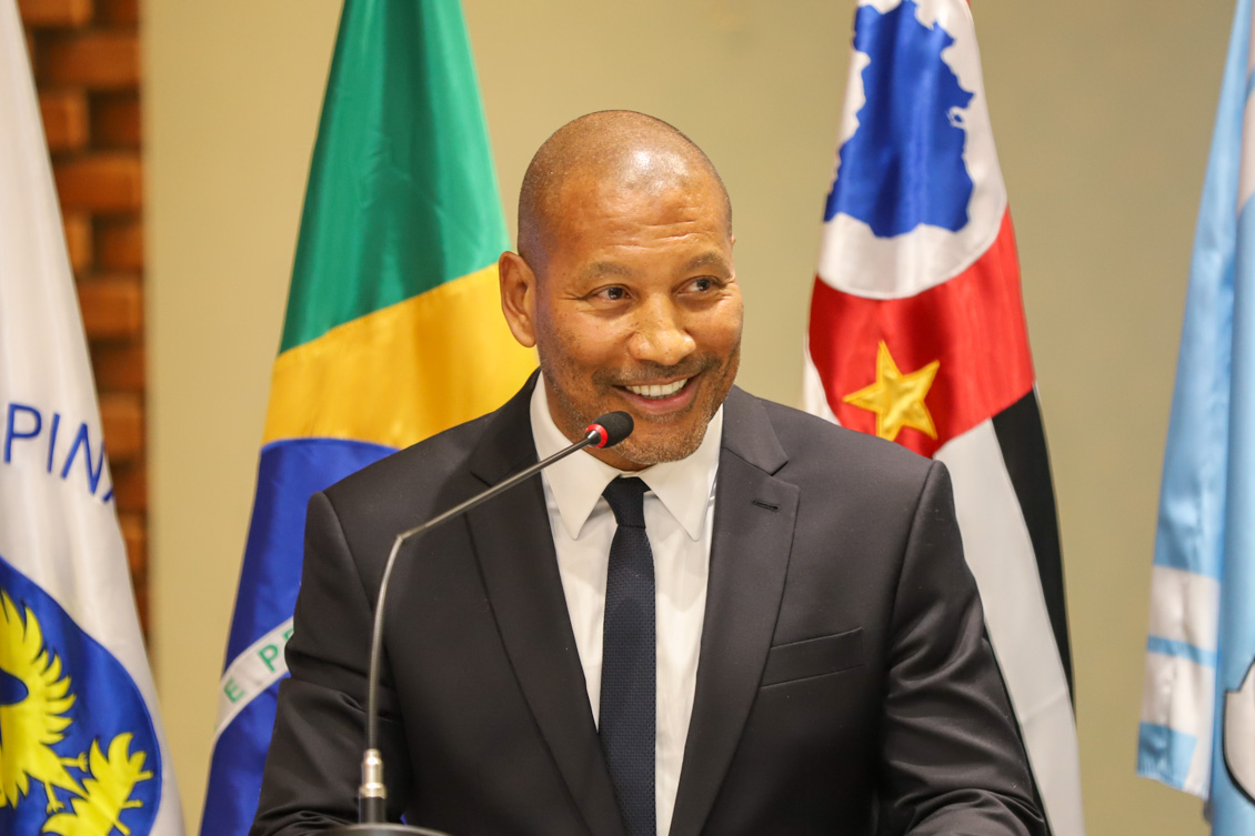 "Mauro Silva fala ao microfone no púlpito, em frente a bandeiras"
