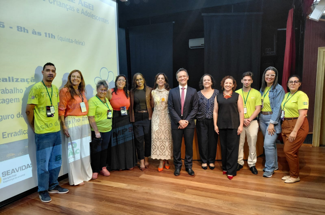 "Foto posada com 12 pessoas no palco, entre homens e mulheres. Entre eles estão Dra. Márcia e Dra. Antônia"