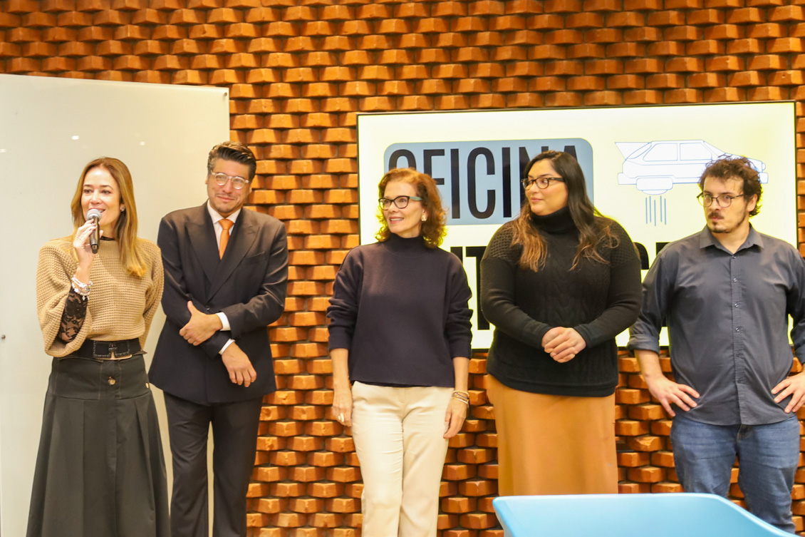 "Dra. Daniela fala ao microfone na mão ao lado do juiz Marcel Marques e outros três integrantes do Colabora 15. Todos de pé"