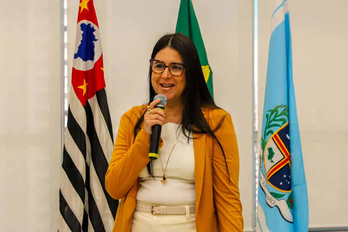 "A juíza Ana Cláudia fala ao microfone em pé"