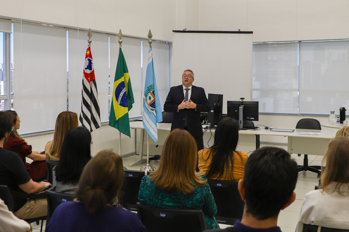 "O professor da PUC em pé fala sendo observado por demais autoridades"