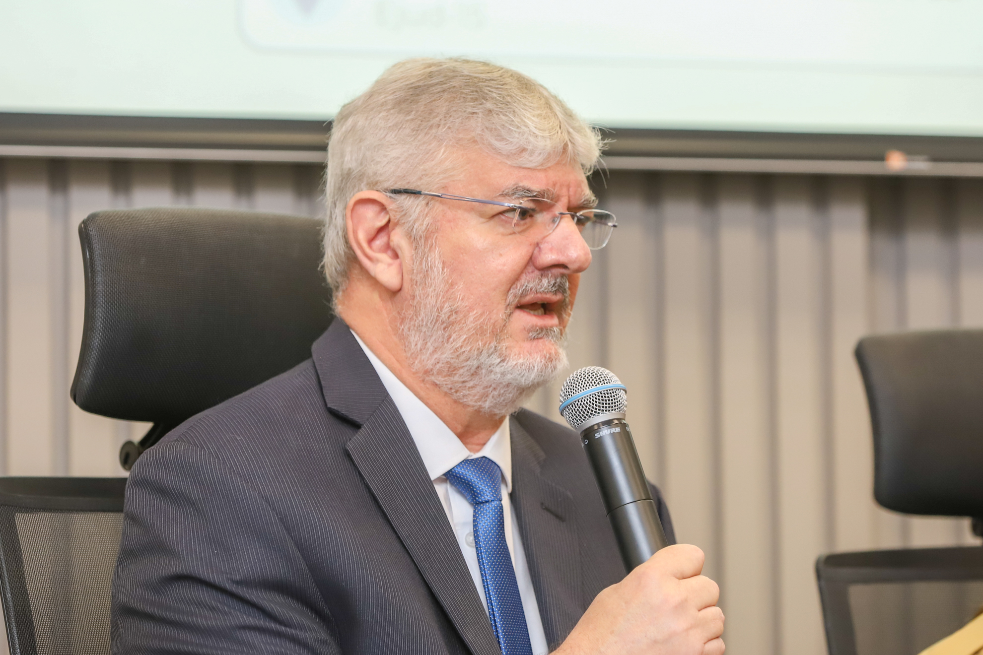 "Dr. Edison fala ao microfone na mesa alta do evento na Ejud-15"