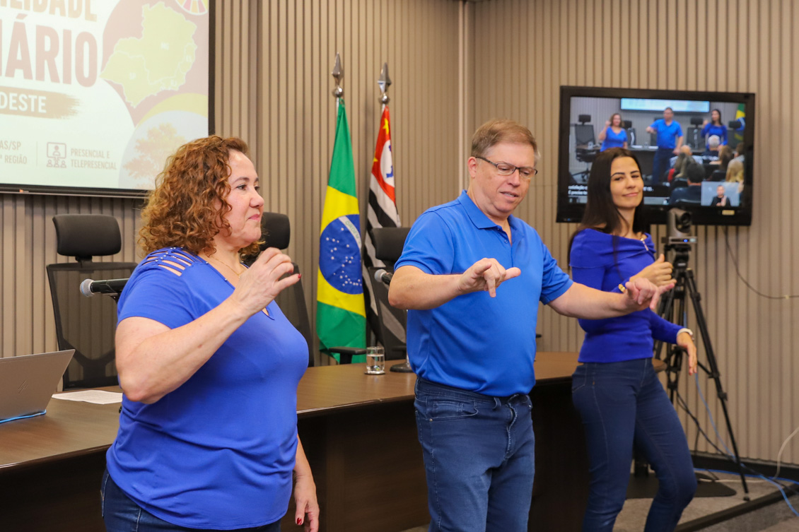 "Coral se libras se apresenta, duas mulheres e um homem em pé fazem gestos"