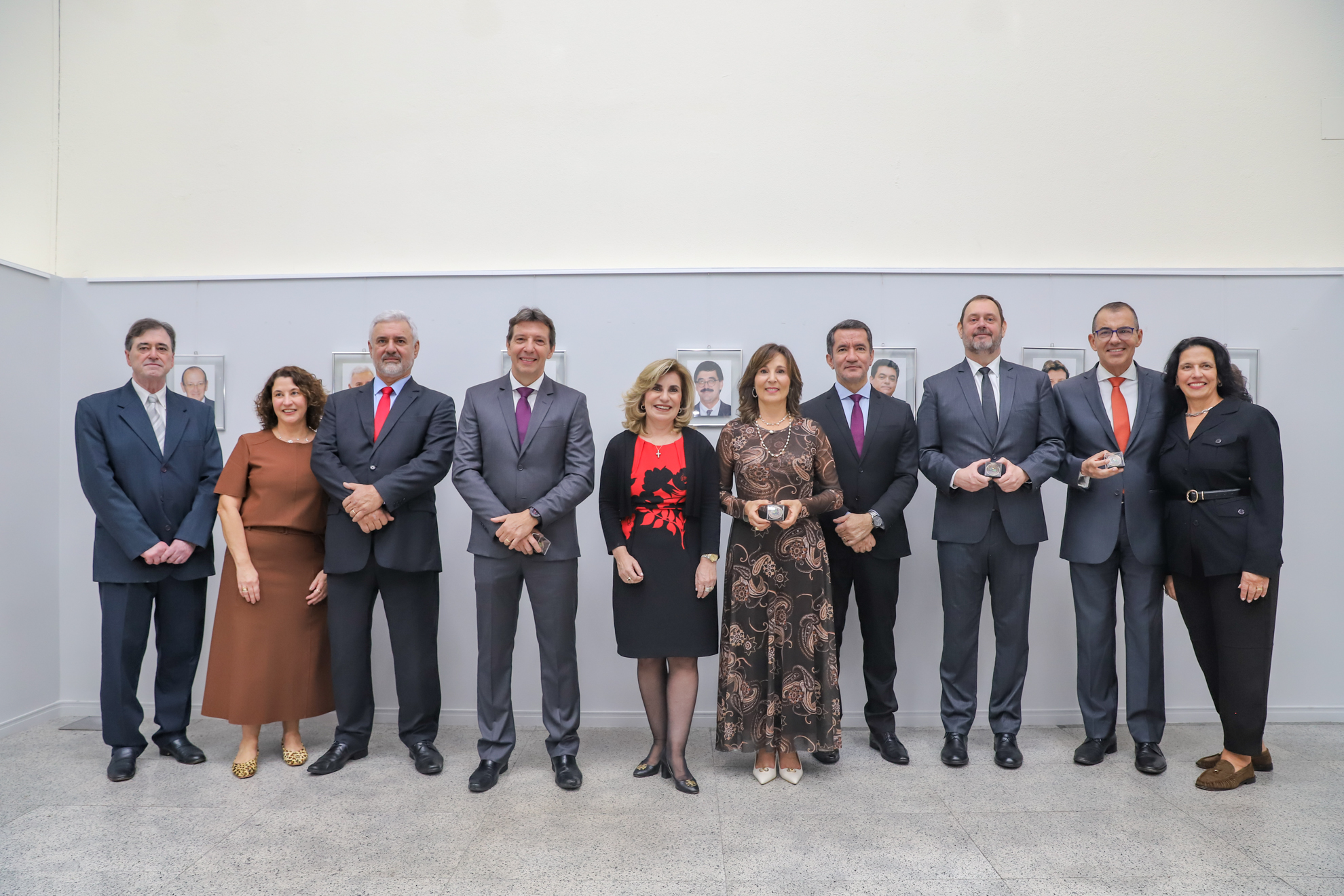 "Dez pessoas posam para a foto em frente a exposição"