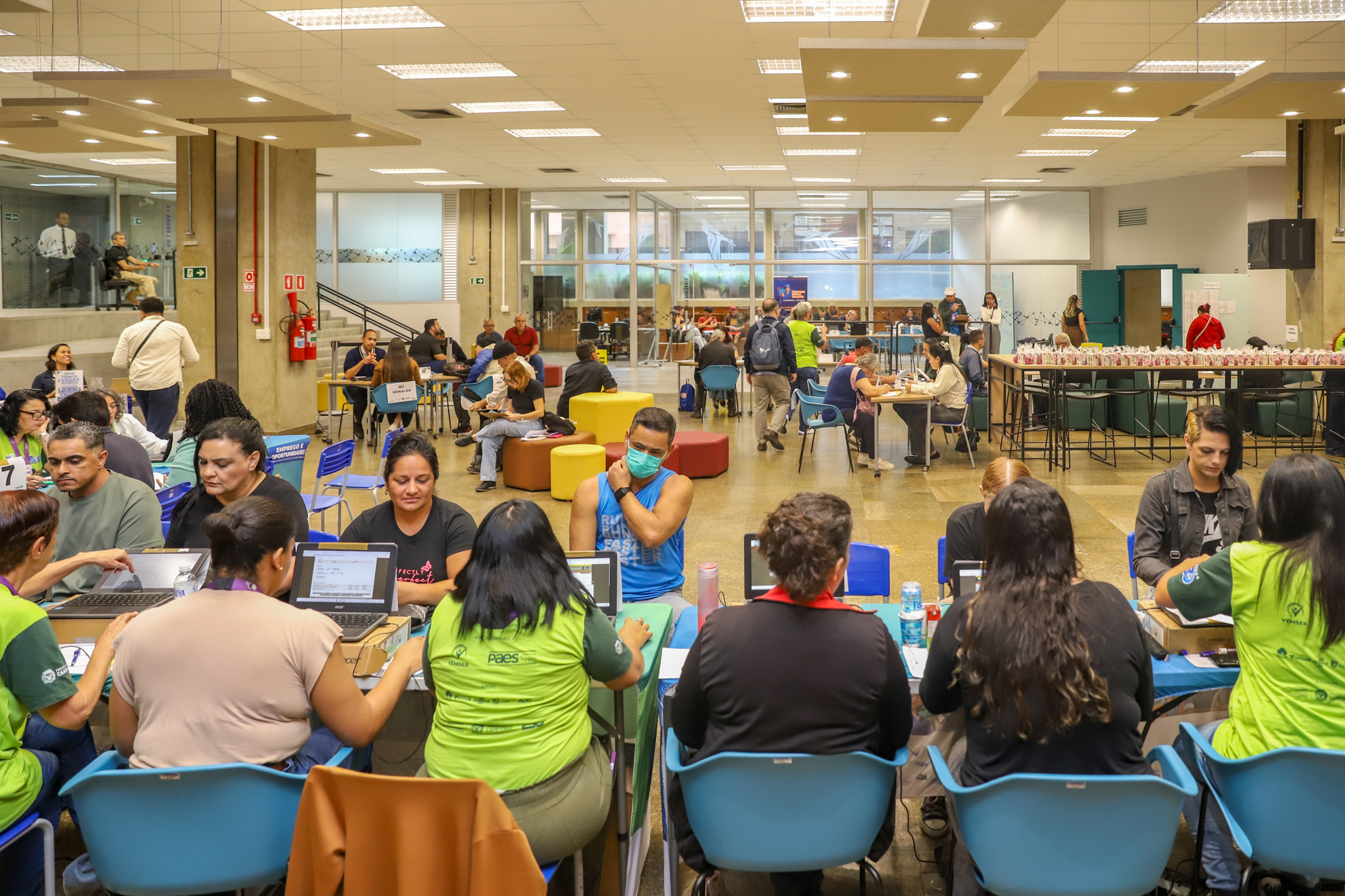 "foto geral do espaço com várias mesas e muitas pessoas sendo atendidas"