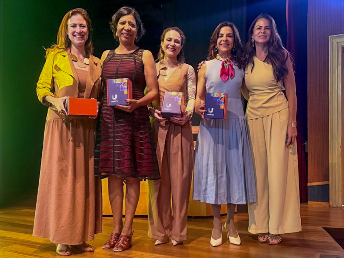 "Cinco mulheres em pé posam para a foto"