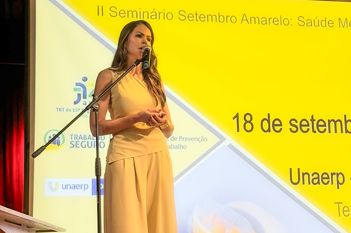 "Uma mulher em pé fala ao microfone"