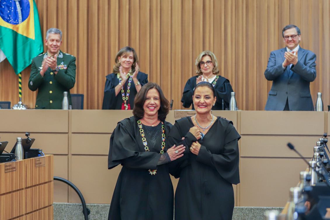 "Dra. Thelma conduz Dra. Juliana sob aplausos dos componentes da mesa alta"