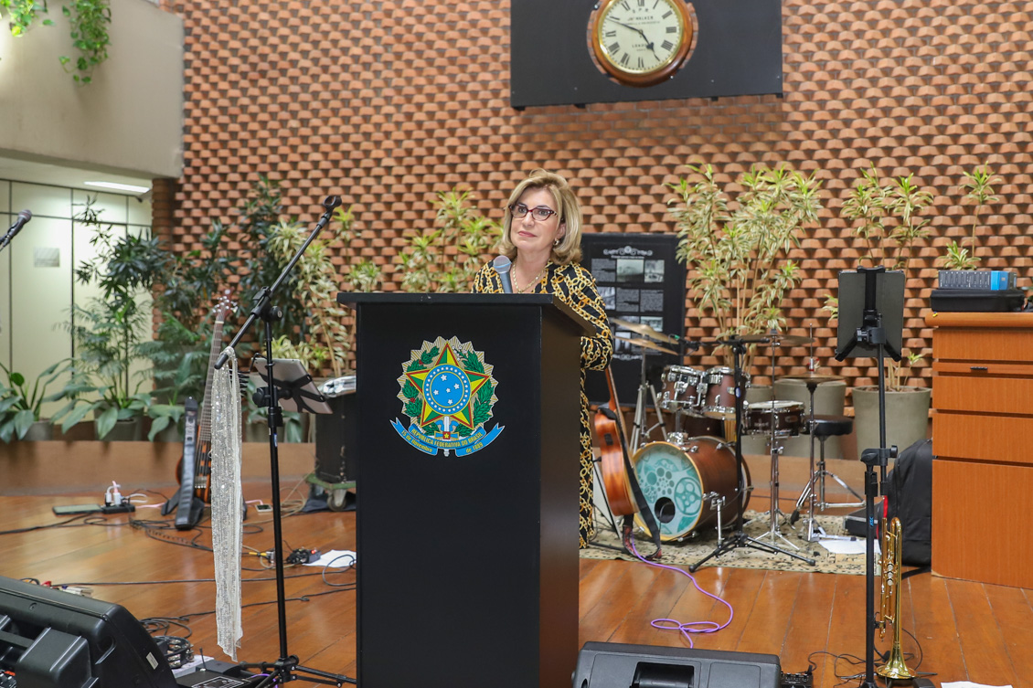 "Dra. Ana Paula fala ao microfone no púlpito"