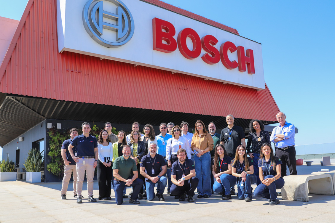 "o grupo posa para foto em frente à fábrica"