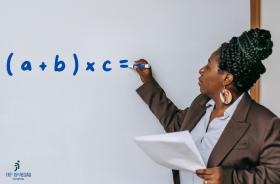 #ParaTodosVerem: Foto retrata uma professora, negra, escrevendo em um quadro branco, com caneta azul.