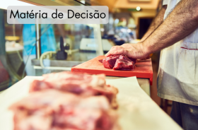 A foto retrata um açougueiro cortando um pedaço de carne.