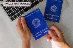 A foto retrata uma mão segurando uma carteira de trabalho.