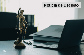 estátua da justiça sobre a mesa de um juiz, que ainda tem papéis e um notebook