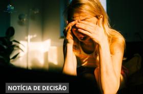 Uma mulher está sentada com as mãos cobrindo o rosto, aparentando tristeza, estresse ou preocupação.