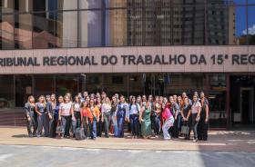 Estudantes e professores estão em pé em frente ao prédio do TRT-15