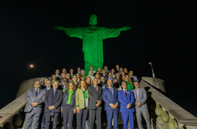 foto noturna de autoridades aos pés do Cristo Redentor iluminado de verde