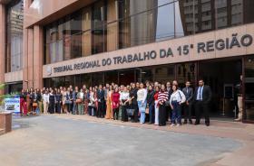 Grupo de pessoas posam para foto na frente do TRT-15.