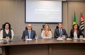 foto da mesa de trabalhos, com componentes, telão e bandeiras ao fundo.