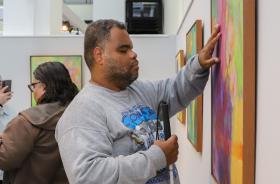 Um rapaz deficiente visual passa a mão em uma das obras da artista.