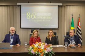 Quatro pessoas estão sentadas e posam para a foto, duas mulheres e dois homens.