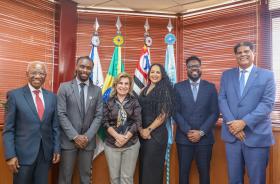 foto posada dos visitantes com a Dra. Ana Paula em frente as bandeiras em seu gabinete