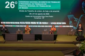 palestrantes em suas poltronas no palco, com telão temático do congresso em tom de verde ao fundo