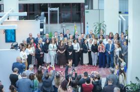 Uma foto do alto com os servidores segurando suas respectivas medalhas. Todos em pé posam para a foto.