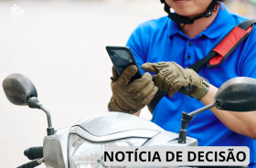 Um homem sentado na moto mexendo no celular.