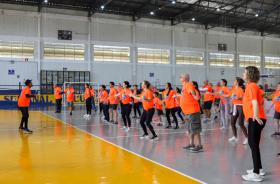 Servidores com camiseta laranja temática da semana fazem exercícios físicos em quadra poliesportiva