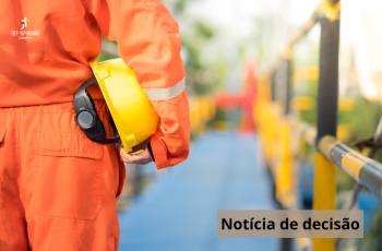 trabalhador de costas, de uniforme laranja, segurando um capacete amarelo numa plataforma
