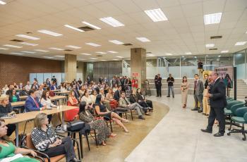 à esquerda da tela, o auditório lotado, à direita, os magistrados em pé, se apresentando